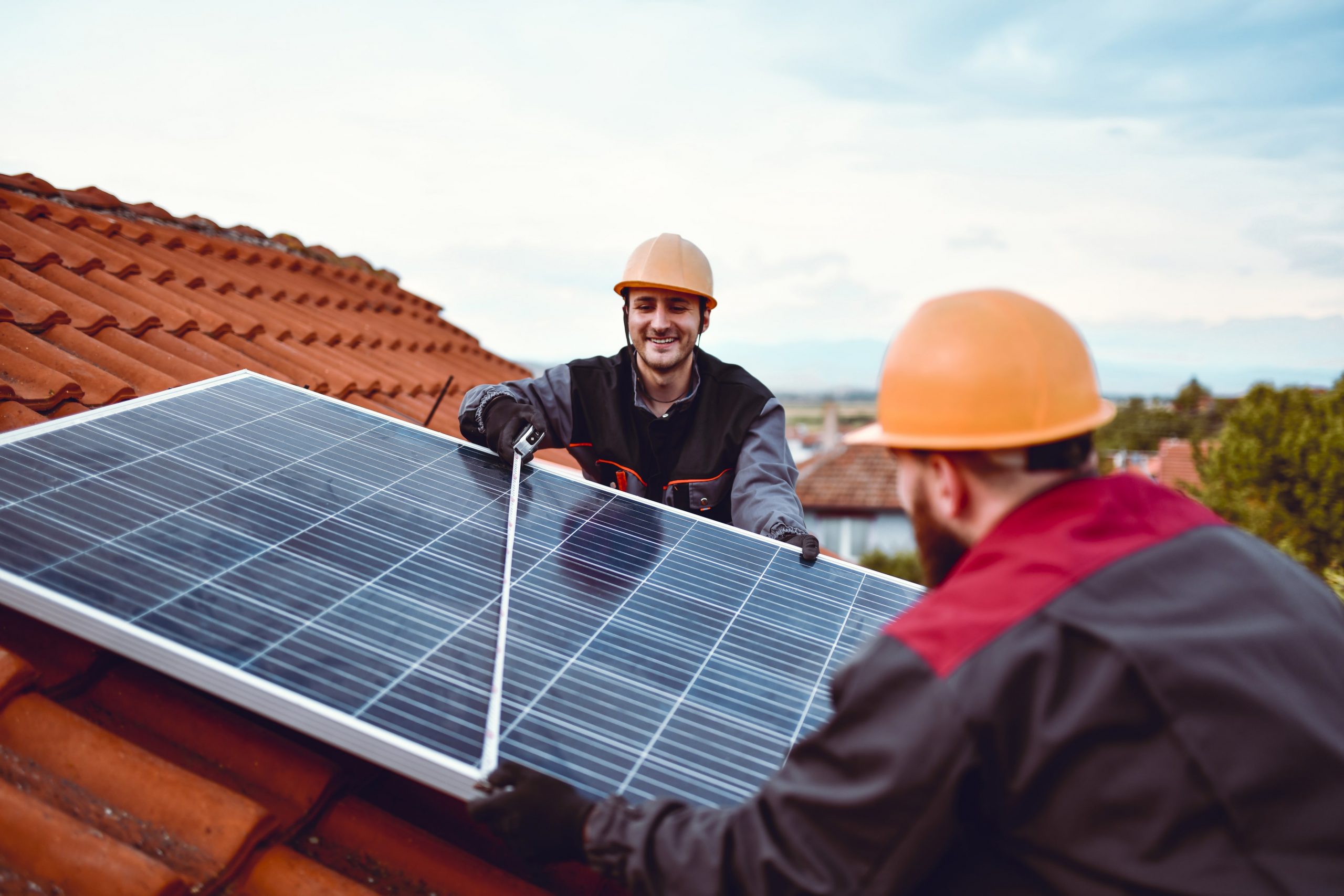 two men installing solar panels on a roof