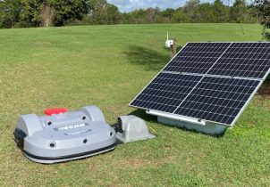 Powershed lawnmower charging next to a solar panel