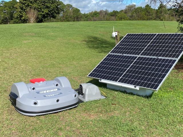 Powershed lawnmower charging next to a solar panel