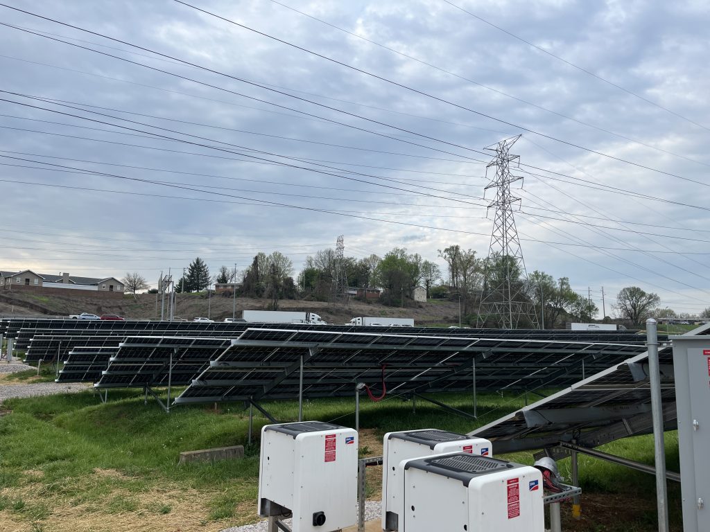 View of inverters and back side of solar modules for ground mounted community solar array