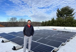 Business owner atop roof with newly installed solar.