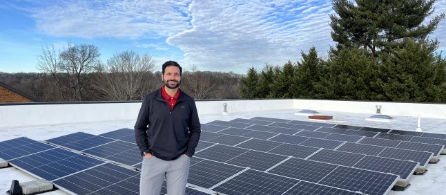 Business owner atop roof with newly installed solar.