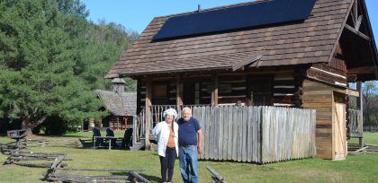 Couple with their solar-powered log cabin that is part of their retreat near the Smoky Mountains
